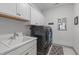 Bright laundry room featuring overhead cabinets, utility sink, modern washer and dryer, and stylish decor at 4105 Bankshire Ln, Raleigh, NC 27603