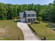 Aerial view of a two-story home with large yard, long driveway, and a playset in a wooded area at 486 S Denise Ave, Coats, NC 27521
