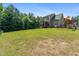 Grassy backyard with play set, the home's back exterior and screened porch at 486 S Denise Ave, Coats, NC 27521