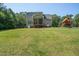 Large backyard with a well-maintained lawn, a wooden play set, and a screened porch at 486 S Denise Ave, Coats, NC 27521