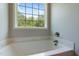 Bright bathroom featuring a white bathtub with marble surround and view to the backyard at 486 S Denise Ave, Coats, NC 27521