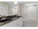 Bathroom with a double sink, black granite countertop, black and white tile, and a tub with shower at 513 Lake Gaston Dr, Fuquay Varina, NC 27526