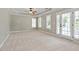Main bedroom features neutral carpet, tray ceiling with ceiling fan, and access to the backyard through french doors at 513 Lake Gaston Dr, Fuquay Varina, NC 27526