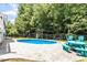 Backyard swimming pool with play-set and outdoor seating, surrounded by lush greenery and a black fence at 513 Lake Gaston Dr, Fuquay Varina, NC 27526
