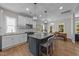 This kitchen has white cabinets, stainless appliances, hardwood floors and a gray island with pendant lighting at 516 Culmore Dr, Fuquay Varina, NC 27526