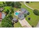Expansive aerial view of a home with an in-ground pool, firepit, attached garage, and lush surrounding greenery at 5405 Overdale Ln, Raleigh, NC 27603