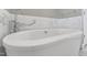 Close-up on a modern white bathtub with chrome fixtures and marble tile surround at 5405 Overdale Ln, Raleigh, NC 27603