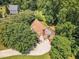 Aerial perspective of home with a deck, brown roof, chimney, lush trees, and green lawn at 6328 Jones Farm Rd, Wake Forest, NC 27587