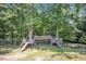 Backyard featuring a large wooden playset with swings and slides, nestled among mature trees at 6328 Jones Farm Rd, Wake Forest, NC 27587