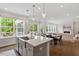 Bright kitchen island featuring quartz countertop, stainless steel sink, and views of the backyard at 74 Permit Ct, Chapel Hill, NC 27517