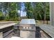 Outdoor kitchen with built-in grill and countertop in a shady backyard setting at 7545 Hasentree Club Dr, Wake Forest, NC 27587