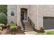 Charming front entrance with brick steps, wrought iron railings, lush landscaping, and an inviting arched doorway at 8132 Wheeler Woods Dr, Apex, NC 27539