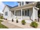 A close-up showcases a covered porch with flowers and white columns in front of home with blue shutters at 820 Water Plant Rd, Zebulon, NC 27597