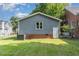 Back exterior with gray siding, a small white door, and green grass at 828 Cotton Pl, Raleigh, NC 27601