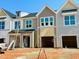 New construction townhomes with various colored siding, bright windows, and attached garages awaiting finishing touches at 87 Ripple Way # 214, Clayton, NC 27520