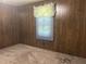 Neutral-carpeted bedroom with window featuring wood-paneled walls and minimalist design at 912 E Pope St, Dunn, NC 28334