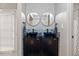 Bathroom featuring double sinks, dark cabinets, decorative mirrors and mosaic tile backsplash at 9801 Honeycutt Rd, Raleigh, NC 27614