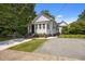 This white home with black shutters and a front porch sits on a lot with mature trees at 1000 College St, Oxford, NC 27565