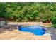 Backyard with a kidney-shaped in-ground pool, surrounded by stone terracing and wooden fencing at 101 Quarryrock Rd, Holly Springs, NC 27540