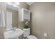Elegant powder room with a pedestal sink, decorative wallpaper, and a stylish wall cabinet at 101 Quarryrock Rd, Holly Springs, NC 27540