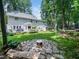 Expansive backyard showcasing a fire pit, well-manicured lawn, patio, and mature trees at 102 Turnberry Ln, Cary, NC 27518