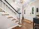 A welcoming foyer features hardwood floors, a staircase with black railings, and a white front door at 102 Turnberry Ln, Cary, NC 27518