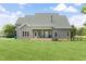 Rear view of a well-maintained house showcasing a large backyard with green lawn and mature landscaping at 106 Garrison Farm Rd, Mebane, NC 27302