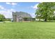 Spacious backyard with a large grassy area, mature trees, and a glimpse of the home's architectural details at 106 Garrison Farm Rd, Mebane, NC 27302
