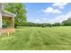 Expansive backyard with lush green grass, mature trees, and a covered patio area, perfect for outdoor living at 106 Garrison Farm Rd, Mebane, NC 27302
