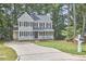 Classic two-story house featuring a lush lawn and a charming front porch amidst a backdrop of mature trees at 106 Rock Nest Ct, Morrisville, NC 27560