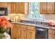 Cozy kitchen featuring wooden cabinets, dark countertops, and a stainless steel sink under a bright window at 106 Rock Nest Ct, Morrisville, NC 27560