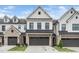 A modern townhouse with white siding, a gray brick facade, a dark garage door, and a well-manicured lawn at 109 Periwinkle Pl, Clayton, NC 27527