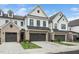 Modern townhouses featuring white siding, gray brick, black accents, and landscaping create an appealing facade at 109 Periwinkle Pl, Clayton, NC 27527
