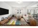 This bright living room has hardwood floors, modern furniture, a patterned rug, and large windows at 109 Periwinkle Pl, Clayton, NC 27527
