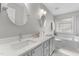 Bright bathroom with double sinks, stone countertops, and a soaking tub next to a window at 12117 Inglehurst Dr, Raleigh, NC 27613