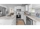 A well-lit kitchen showcasing white cabinets, stainless steel appliances, and a woven runner on wood floors at 12117 Inglehurst Dr, Raleigh, NC 27613