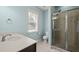 Bright bathroom with a large window, walk-in shower, toilet and vanity with white countertop and stainless fixtures at 12216 Kyle Abbey Ln, Raleigh, NC 27613