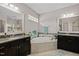 Bright bathroom showcasing dual vanities, a soaking tub, and ceramic tile flooring at 12216 Kyle Abbey Ln, Raleigh, NC 27613
