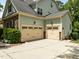 Spacious three-car garage with tan doors, providing ample parking and storage with stone and siding accents at 12216 Kyle Abbey Ln, Raleigh, NC 27613
