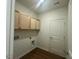 Well-lit laundry room with wood-look flooring and overhead cabinets at 125 Fraiser Fir Way, Lillington, NC 27546