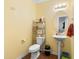 Bathroom with pedestal sink, shelving, and laminated floor, offering functional simplicity at 131 Botanical Ct, Bunnlevel, NC 28323