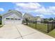 View of the driveway leading to the garage, surrounded by green grass and black fencing at 141 Beldenshire Way, Holly Springs, NC 27540