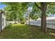 Large, shady backyard with lush green grass, mature trees, and white fence at 141 S Broad E St, Angier, NC 27501