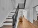 Bright hallway featuring hardwood floors and a classic staircase with dark wood accents at 141 S Broad E St, Angier, NC 27501