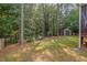 View of the backyard with mature trees, storage shed, lush green lawn and woods beyond at 1612 Old Bramble Ln, Fuquay Varina, NC 27526