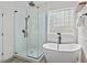 Bright bathroom features a free-standing tub, shower, and window block for privacy at 1612 Old Bramble Ln, Fuquay Varina, NC 27526