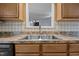 Close up of the stainless steel kitchen sink featuring modern fixtures, hardwood cabinets, and a tile backsplash at 191 Bridle Dr, Angier, NC 27501