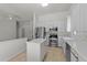 A well-lit kitchen featuring white cabinets, an island, stainless steel appliances, and neutral tile flooring at 206 Lake Brandt Dr, Cary, NC 27519