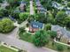 Aerial view of a neighborhood showcasing well-manicured lawns, mature trees, and a beautifully designed brick home at 2224 Narrawood St, Raleigh, NC 27614