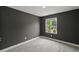 Cozy bedroom with a window view of lush greenery, modern gray walls, and plush carpet at 2225 Millbank Village Ct # 101, Raleigh, NC 27610